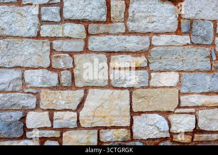 Rough stone wall texture with natural pattern. Close-up of a rustic stone wall made of irregular blocks and mortar, showing natural textures, colors Stock Photo