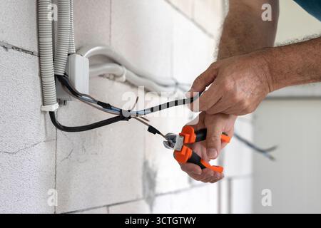 Electrician, repairman working to install an electrical installation on a construction site of a new house Stock Photo