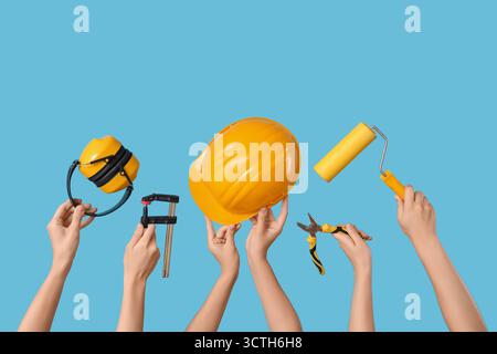 Hands with hardhat and construction tools on blue background Stock Photo