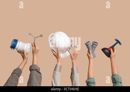 Hands with hardhat and plumber supplies on beige background Stock Photo