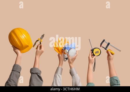 Hands with hardhat and construction tools on beige background Stock Photo