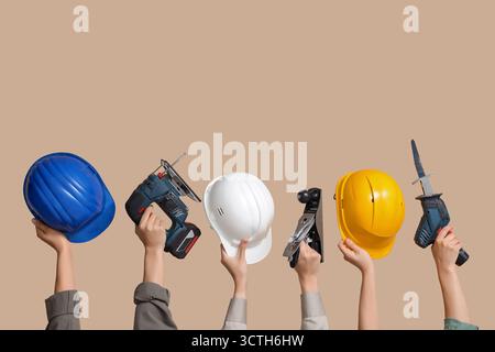 Hands with hardhats and construction tools on beige background Stock Photo