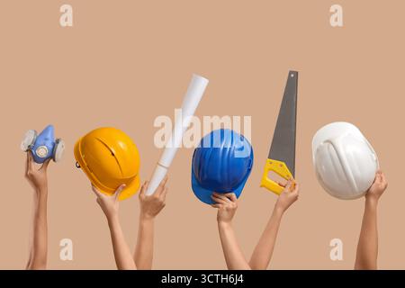 Hands with hardhats and construction tools on beige background Stock Photo