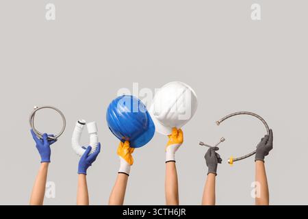 Hands with hardhat and plumber supplies on grey background Stock Photo