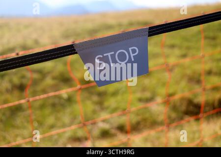 Stop Sign on Fence in a Grassy Field in mountains Stock Photo