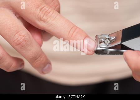Hand is carefully using nail clippers to trim fingernails, emphasizing personal grooming and hygiene in a clean, inviting indoor setting with natural Stock Photo