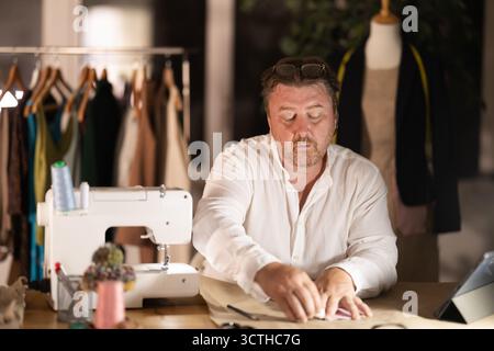 Middle-aged male dressmaker drawing detail on paper with chalk Stock Photo