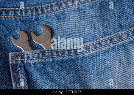 wrench in jeans pocket. Two wrenches in the back pocket of a pair of blue jeans. Stock Photo