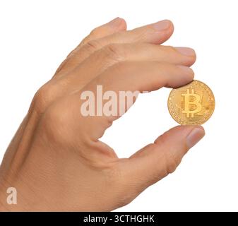 A hand is holding a golden bitcoin coin against a plain background, showcasing its design and shine in bright light. Stock Photo
