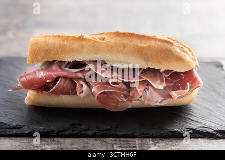 Traditional Spanish Serrano Ham Sandwich on wooden table Stock Photo