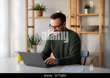 Success man typing on laptop, communicating online distantly working or studying on computer at home Stock Photo