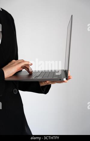 Minimalist vertical photo of female hands working on a laptop with touchpad. Modern concept of remote work, technology, and digital productivity.  Stock Photo