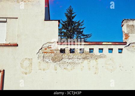 Old house with faded “Gorenje” ad traces in winter sun, shot on expired film with a light-leaking Olympus. Analog vibe. Stock Photo