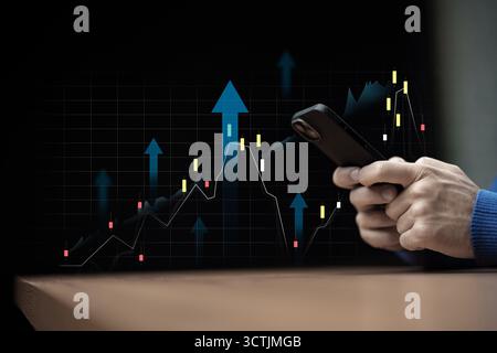 Active trader analyzes market trends using smartphone in a dark setting Stock Photo