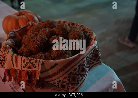 Rustic pumpkin bread rolls, bread buns in a basket, lined with a colorful traditional Cretan woven towel and a real pumpkin in the background. Stock Photo