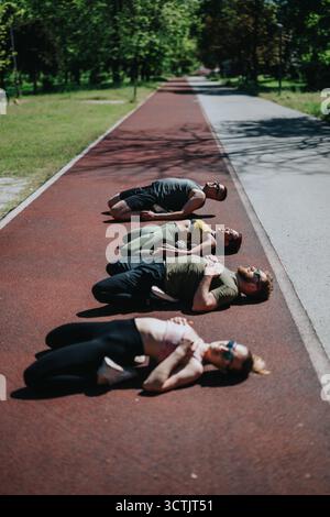 Group of diverse individuals lying on a track under the sun Stock Photo