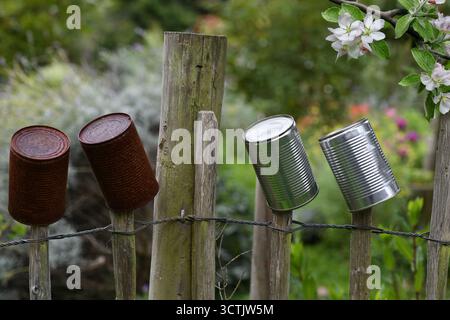 Tin cans along a picket fence Stock Photo