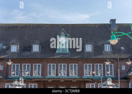 A large building with a slate roof and a central tower clock. Lanterns stand in front of it in the square. Stock Photo