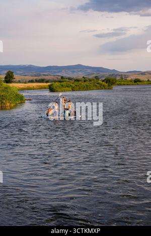 Young people enjoy rafting down the Gallatin River in western Montana on a beautiful summer evening. Stock Photo