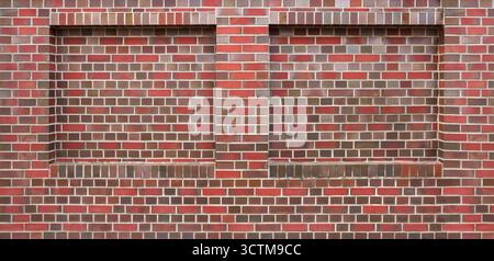 Brown grey red patterned brick wall with two bricked-up window niches Stock Photo
