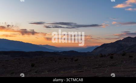 Sunset glow over Death Valley��s mountain ridges and layered terrain, a tranquil desert scene of scale and warmth. Stock Photo