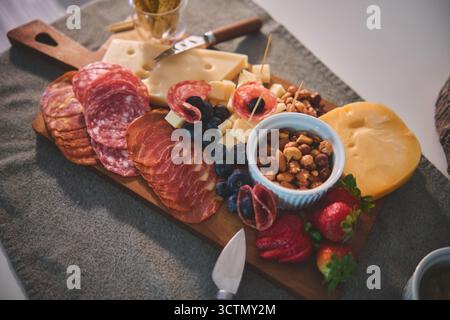 Charcuterie board served on a gray placemat, featuring various appetizers for a snack party Stock Photo