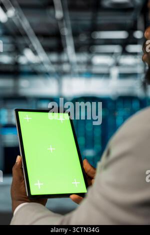 Server farm computer scientist using mockup tablet to repair equipment storing datasets. IT expert using green screen device to do debugging on mainframes doing computational operations Stock Photo