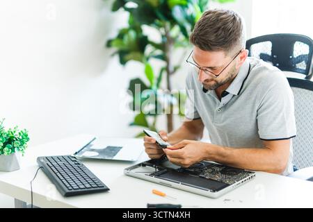 Handsome engineer repairing laptop computer. Stock Photo