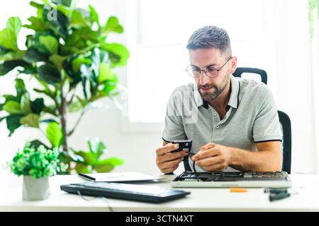 Handsome engineer repairing laptop computer. Stock Photo