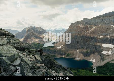 Mountain Vista: Rugged peaks overlook serene lakes under a cloudy sky. Stock Photo