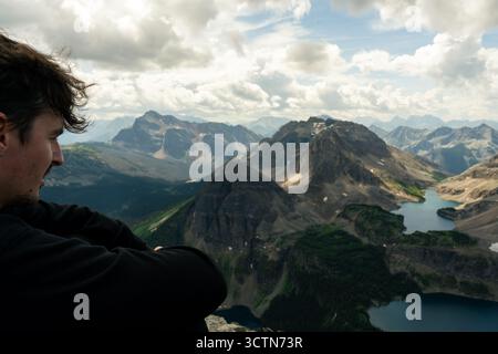 Contemplative hiker enjoys vast mountain vista on a sunny day. Stock Photo