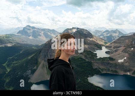 Person enjoying mountain view, dressed in black on a sunny day in nature. Stock Photo
