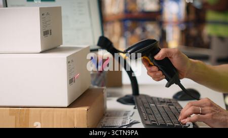 Asian male staff uses handheld scanner to register airway bill information, updating the package tracking software in real time with barcode reader and shipment details. Stock room. Camera B. Stock Photo