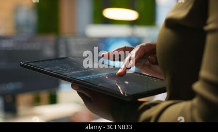 Close up of engineer using tablet to write code, developing machine learning APIs. IT professional troubleshooting software errors and faults using artificial intelligence, camera A Stock Photo