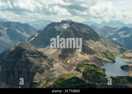Dramatic mountain peaks rise above a glacial lake under a cloudy sky. Stock Photo