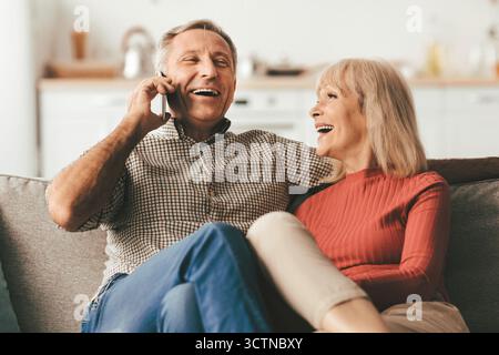 Happy Senior Couple Talking On Phone And Laughing At Home Stock Photo