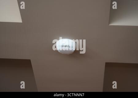 Smoke detector installed on a ceiling in a building Stock Photo