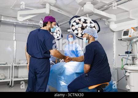 Surgeons Handshake in Operating Room Stock Photo