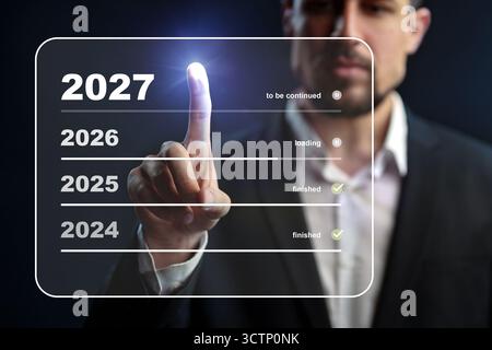 Man interacts with futuristic display showing progress from 2024 to 2027 Stock Photo