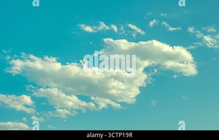 White fluffy clouds in a blue sky. A peaceful image of fluffy clouds drifting across a clear  sky on a sunny day. Use for in weather, relaxation and e Stock Photo
