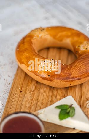 Turkish bagel with cheese and jam on wooden board. Traditional Turkish bagel served on a wooden board. Turkish breakfast atmosphere. Selective focus. Stock Photo