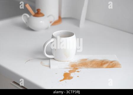 Cup and paper towel with coffee stains on table in kitchen Stock Photo