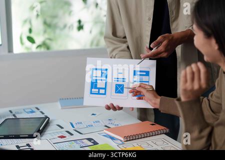 UI UX Design Review. Team discussing mobile app wireframes and features. Stock Photo