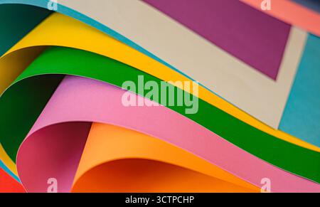 Close-up of curled sheets of colored paper. The composition emphasizes shape and negative space. Making it useful as a minimal design and modern backg Stock Photo