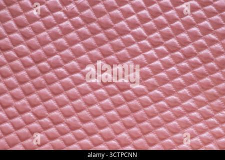 Close-up of soft pink quilted fabric with a diamond pattern. Showcasing its plush texture and subtle sheen. Ideal for backgrounds or textile designs. Stock Photo