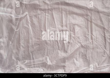 Top view of a wrinkled white plastic sheet. The folds and creases create abstract textures, reflecting light and shadow. Suitable for backgrounds. Stock Photo