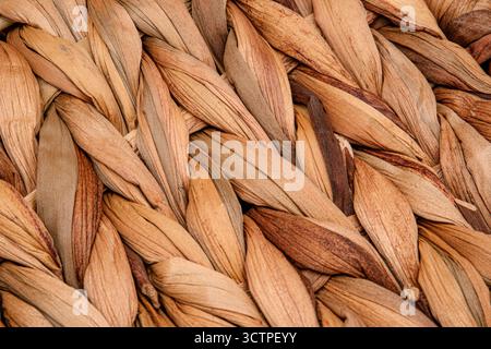 Close-up of a woven natural fiber texture in earthy brown tones. Interlaced dried plant materials create organic pattern. Perfect for eco-friendly. Stock Photo