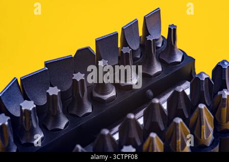 Close-up view comprehensive set of dark metallic screwdriver bits. Featuring various bits types like flathead, Torx and Phillips. Stock Photo
