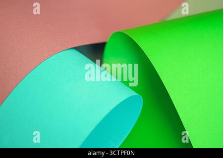Close-up view of colorful sheets of paper in cyan, green and pink tones. Rolled and curved into abstract shapes. The vibrant composition. Stock Photo