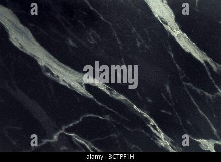 Dark black marble surface with elegant white and grey veins running across. A luxurious stone texture perfect for architecture, countertops, flooring Stock Photo